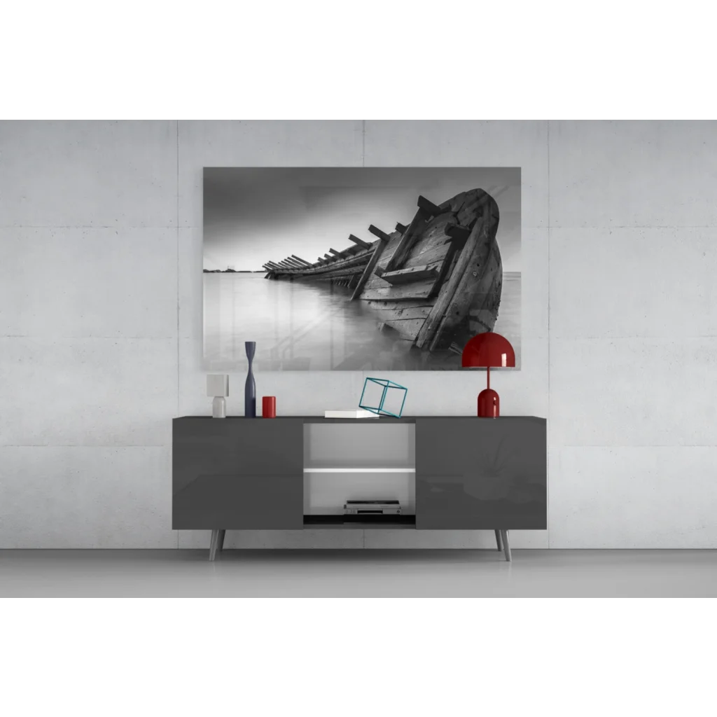 Black-and-white glass wall art of weathered boat on water