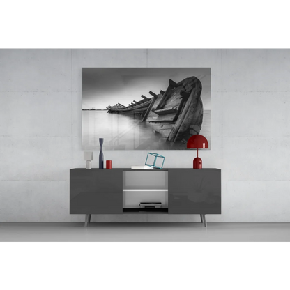 Black-and-white glass wall art of weathered boat on water