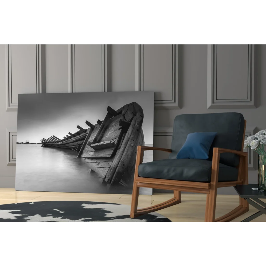 Black-and-white glass wall art of weathered wooden boat on calm water