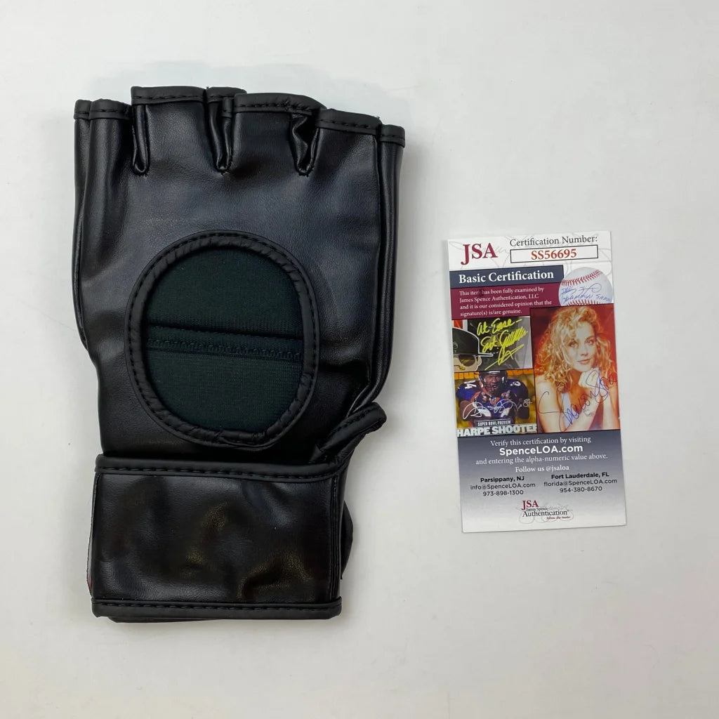Black leather fingerless UFC fight glove with palm support, wrist strap, and JSA card