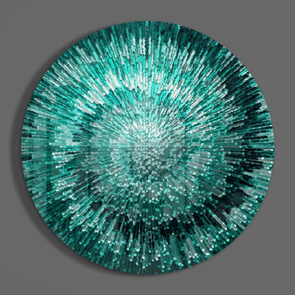 Circular glass wall art with radiating teal and white glass shards creating a starburst pattern against a gray background.