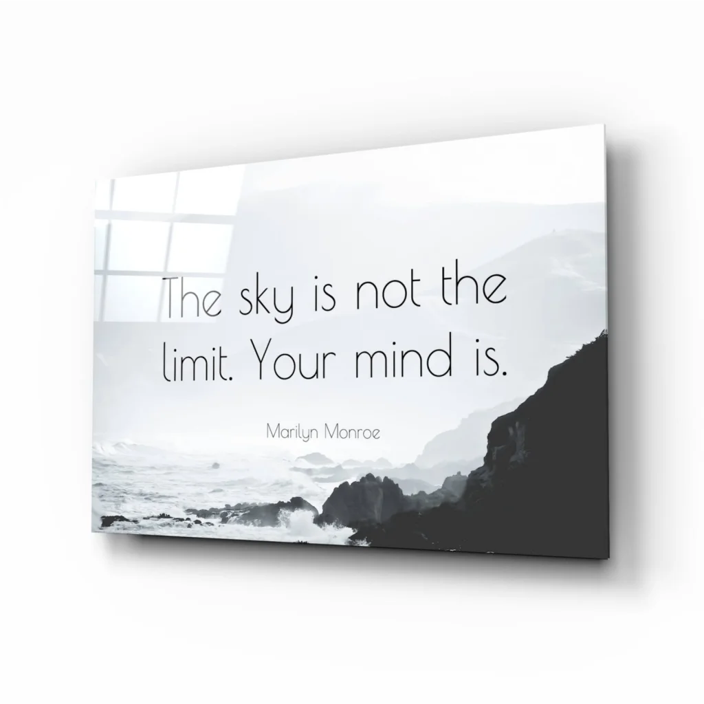 Sleek minimalist glass wall art of monochrome coastal landscape with the sky is not the limit quote