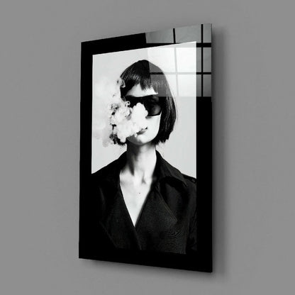 Black framed glass wall art print of woman exhaling smoke in sunglasses