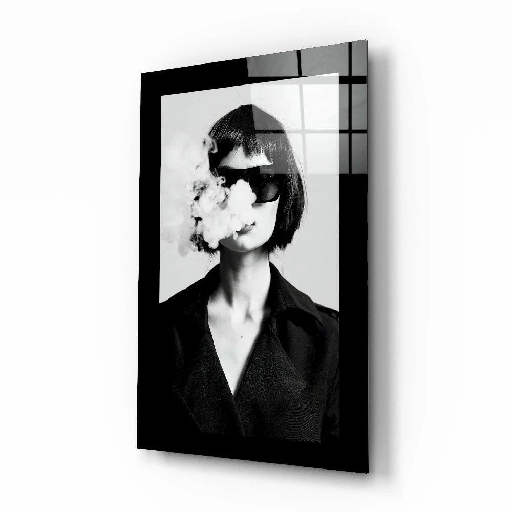 Black framed glass wall art of woman in sunglasses exhaling smoke
