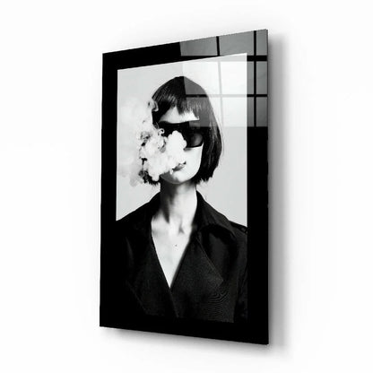 Black framed glass wall art of woman in sunglasses exhaling smoke