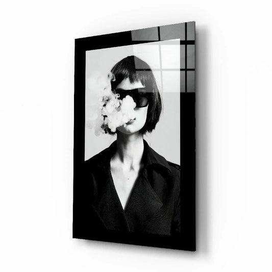 Black framed glass wall art of woman in sunglasses exhaling smoke