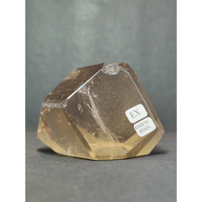 A translucent golden-yellow citrine crystal with faceted geometric cut and internal inclusions in quartz polished free form sculpture