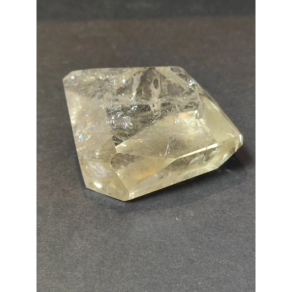 A translucent yellowish smoky clear quartz polished free form sculpture with faceted geometric shape and internal inclusions