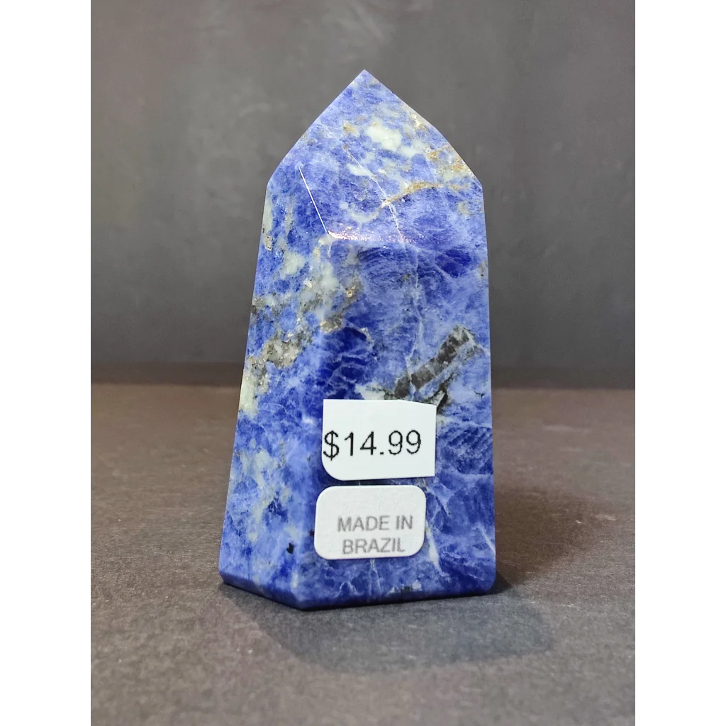 A vibrant blue sodalite polished obelisk tower sculpture with golden and white mineral inclusions and smooth finish