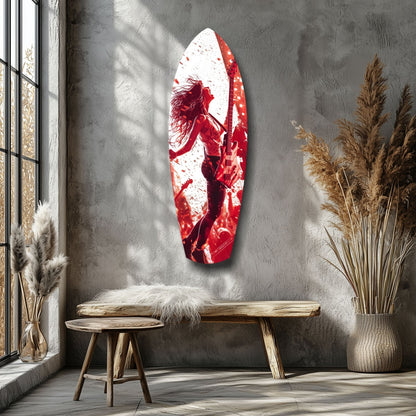 Red and white glass surfboard wall art depicting a woman musician with guitar, displayed above wooden bench in minimalist interior with dried grasses.