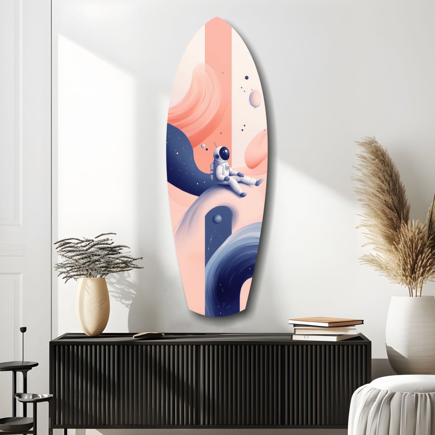Elongated oval glass wall art featuring an astronaut floating among coral and navy planets against a peachy gradient background, displayed above a black console table.