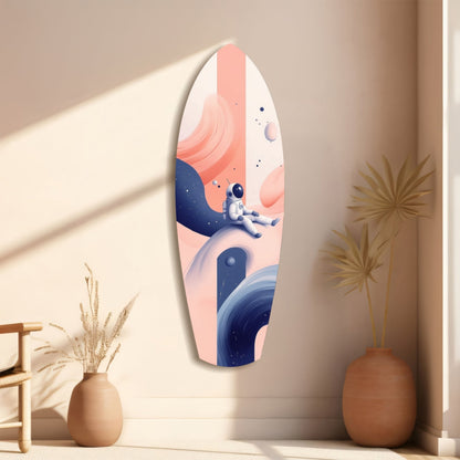 Oval glass wall art displaying an astronaut sitting on a planet amid pink and blue cosmic scenery, hung in a minimalist beige room with dried plants.