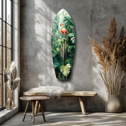 Elongated surfboard-shaped glass wall art featuring a red flamingo amid green tropical foliage, displayed above a wooden bench in a minimalist room.
