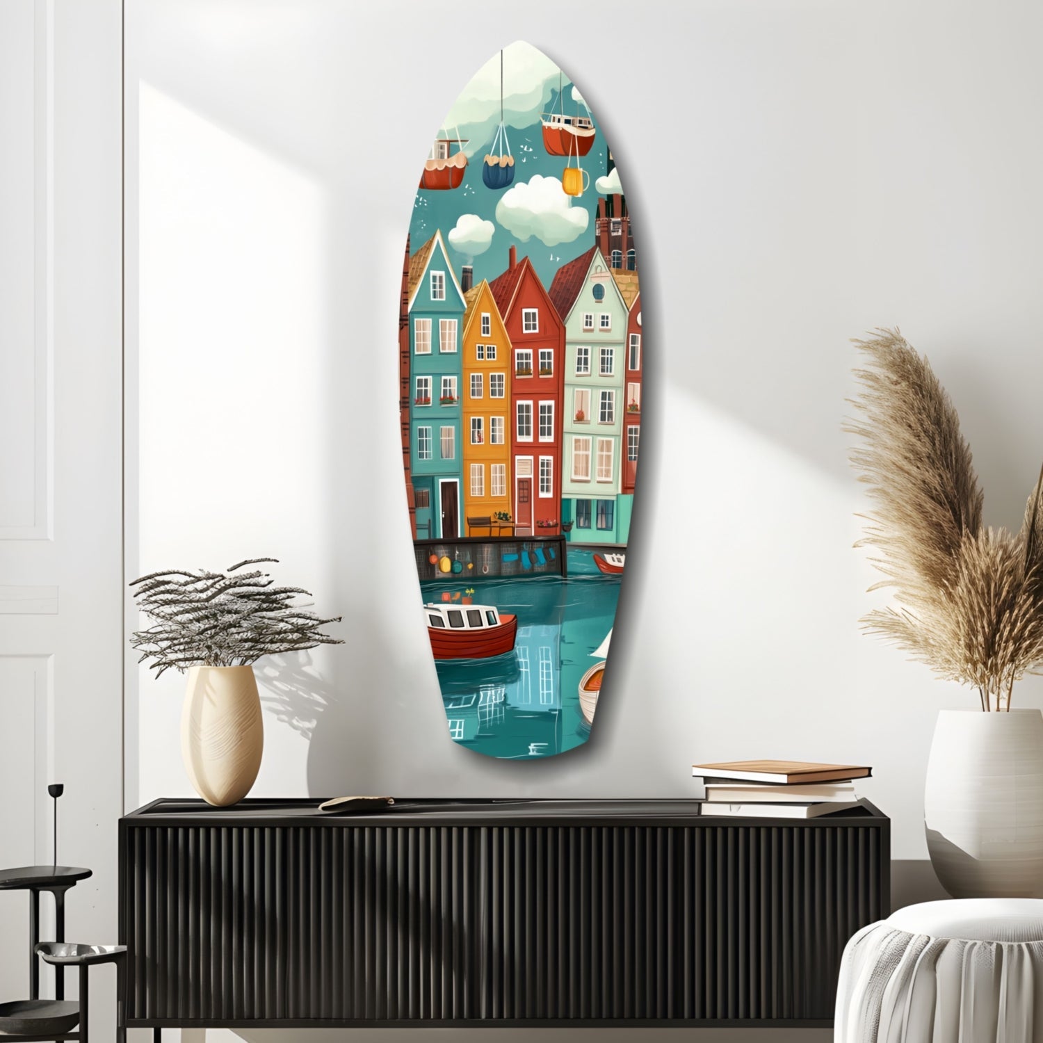 Oval glass wall art depicting colorful waterfront buildings and boats hanging above a black ribbed console table with decorative vases and books.
