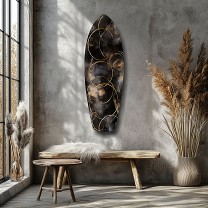 Dark glass wall sculpture with gold circular wire overlays hung above a wooden bench in minimalist interior with pampas grass.