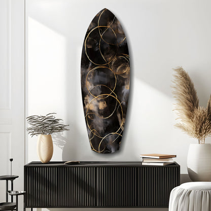 Black textured glass oval wall art with gold circular line designs, displayed above a ribbed black console table in a modern interior setting.
