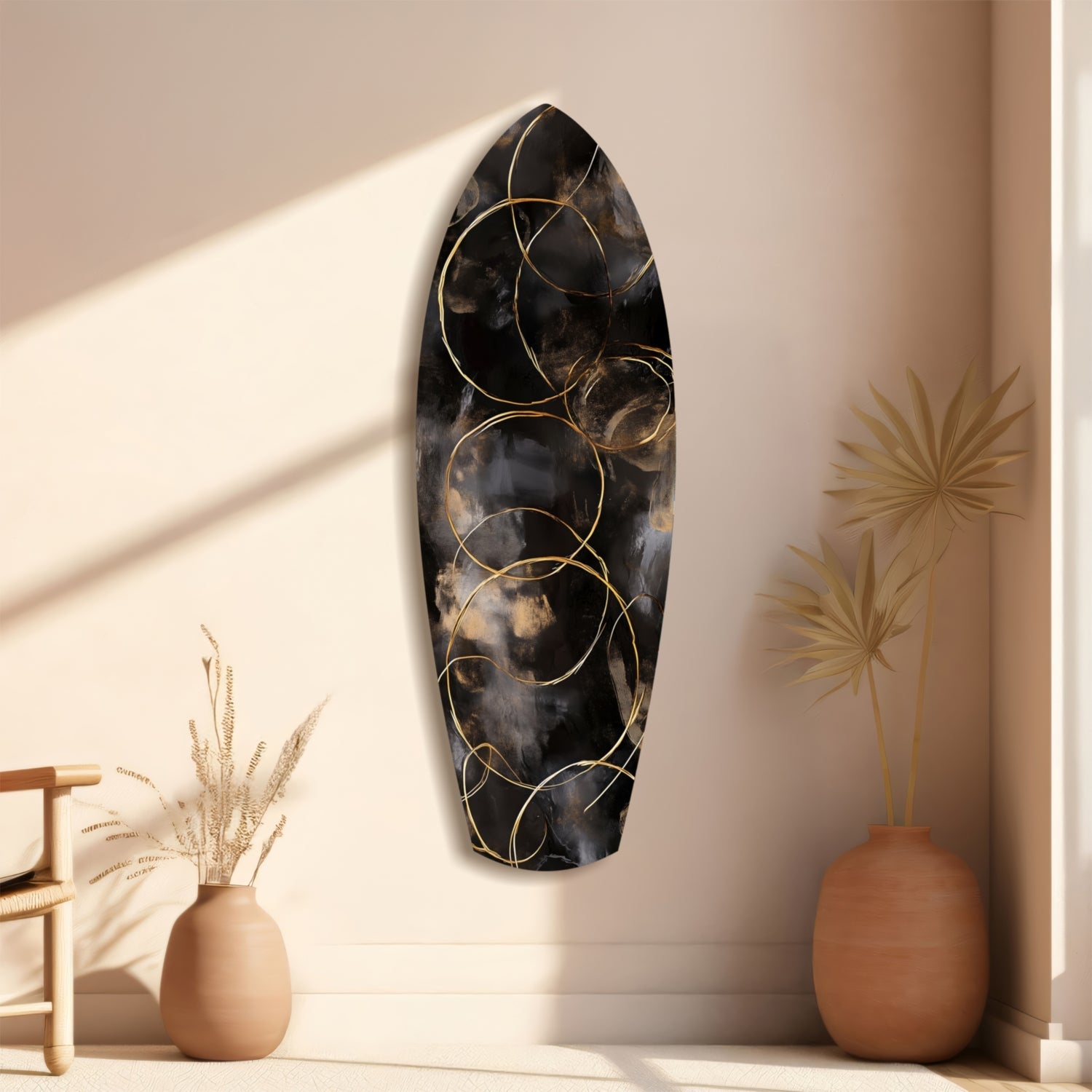 Black glass wall art with gold circular patterns displayed on beige wall between terracotta vases with dried botanicals.