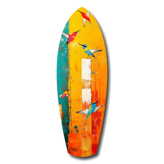 Colorful surfboard-shaped glass wall art featuring five painted hummingbirds against gradient yellow, orange, teal, and red background with distressed finish.