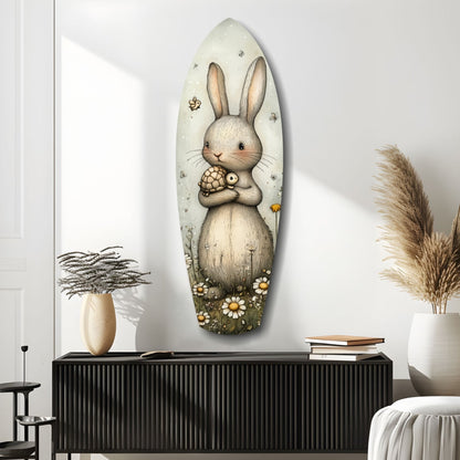Oval glass wall art depicting a cream-colored rabbit holding a turtle, surrounded by flowers and insects, mounted above a black ridged cabinet in a minimalist interior.