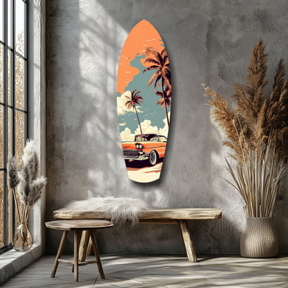 Surfboard-shaped glass wall art displaying a vintage orange car, palm trees, and orange sky, mounted on grey textured wall above wooden bench.