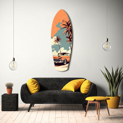Surfboard-shaped glass wall art displaying vintage orange car, palm trees, and orange sky above black sofa with yellow pillows.