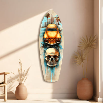 Surfboard-shaped wall art displaying orange vintage car, skull, and palm trees against cream wall with dried plants beside it.