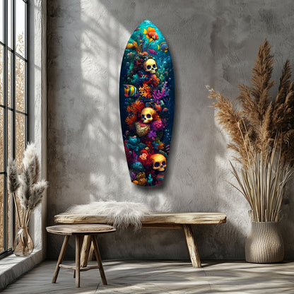 Vibrant glass wall art surfboard displaying colorful coral, tropical fish, and golden skulls mounted in minimalist room with wooden bench and pampas grass.