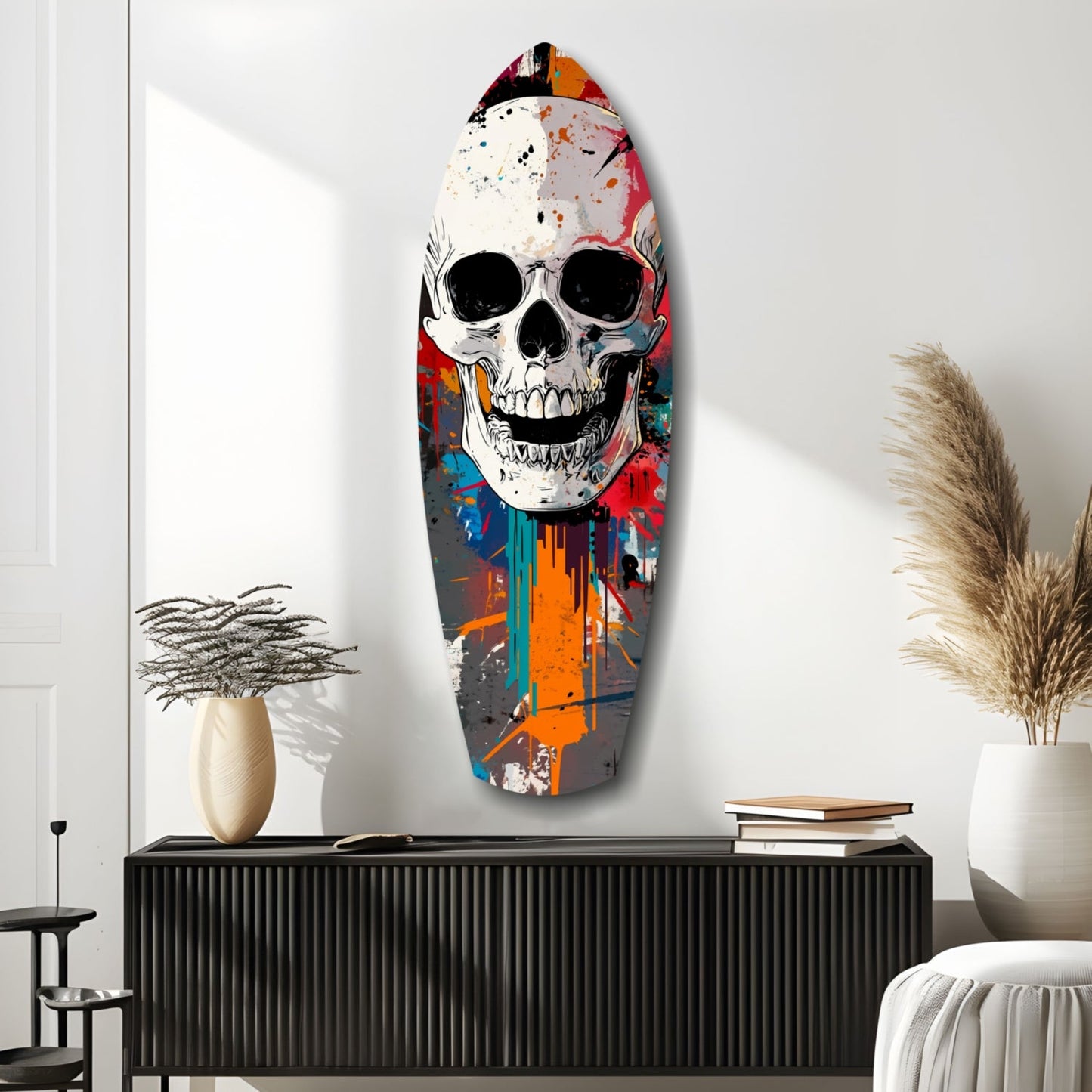 Colorful street art skull glass wall art mounted above black cabinet with decorative vases and pampas grass in minimalist room setting.