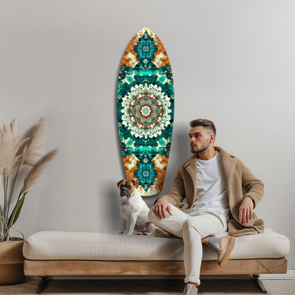 Man and dog seated on bench beside surfboard-shaped glass wall art featuring teal, emerald, and gold mandala pattern.