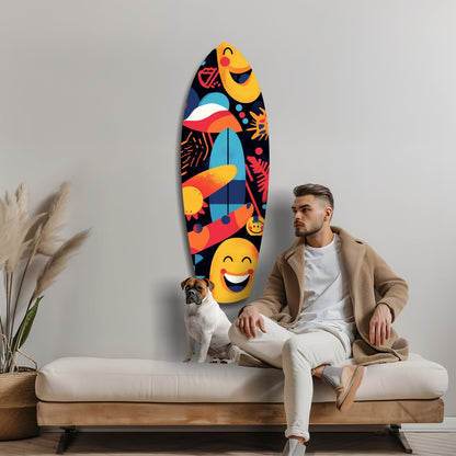 Man and dog sitting on cream sofa beneath colorful surfboard-shaped glass wall art featuring smiling emoji faces and tropical designs on black background.