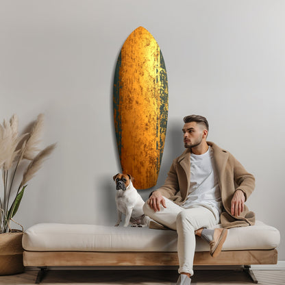 Man with dog sitting on bench beside large golden textured glass wall art panel against gray wall.