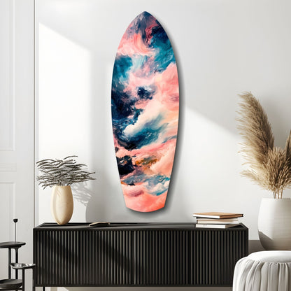 Surfboard-shaped glass wall art with swirled pink, teal, and navy abstract patterns displayed above a black ribbed cabinet in a minimalist room.