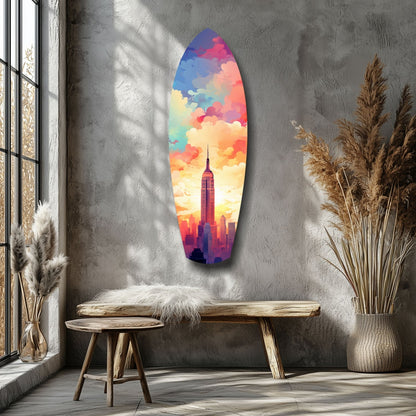 Colorful glass wall art depicting Empire State Building silhouette against vibrant rainbow sunset clouds, displayed in minimalist room setting.
