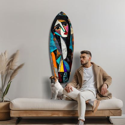 Man and dog sit on cream sofa beside colorful abstract female face glass wall art with geometric shapes in blue, orange, and black.
