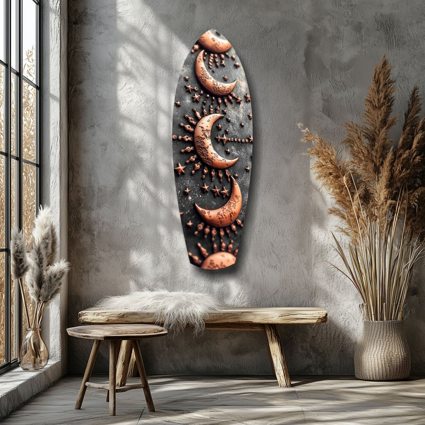 Copper moon and star motifs on dark glass panel displayed on gray wall above wooden bench with pampas grass decor.