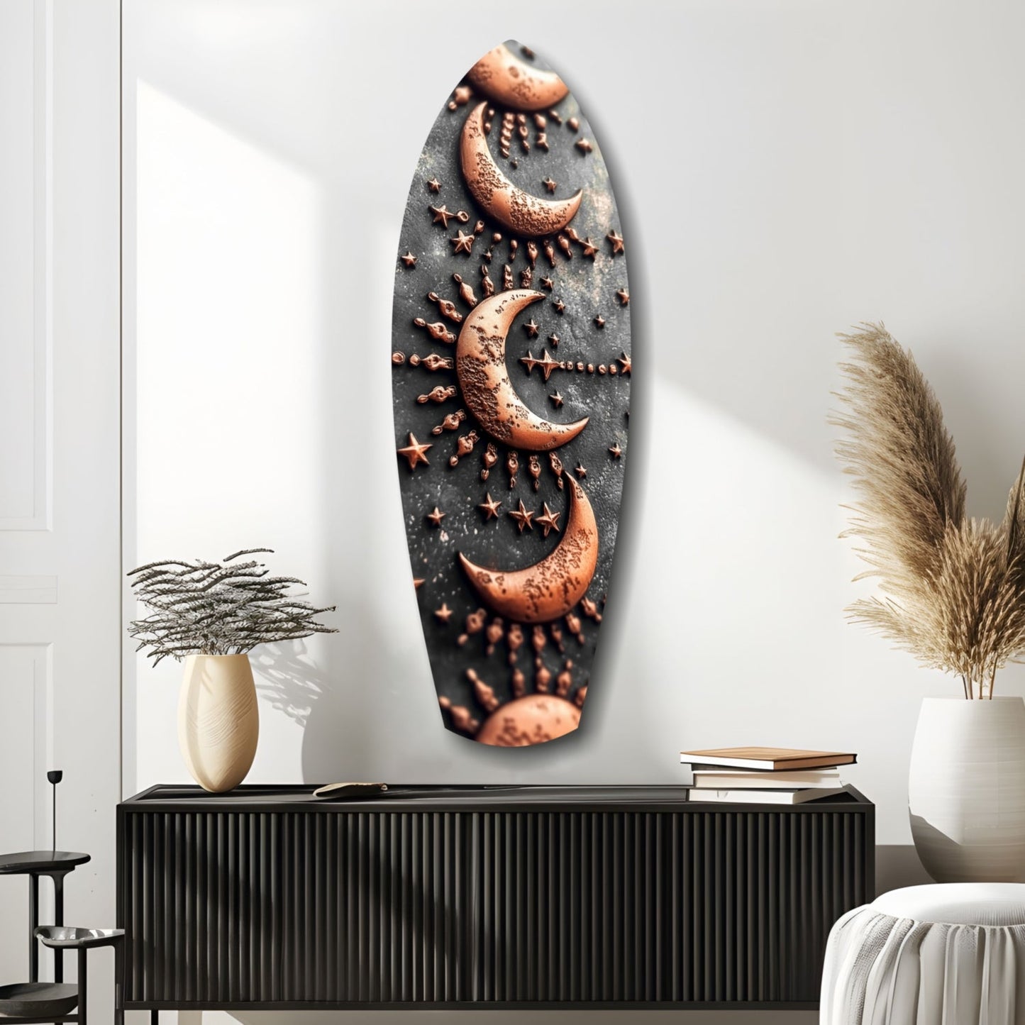 Oval copper and black glass wall art featuring three crescent moons with star details, displayed above a black cabinet in a minimalist interior.