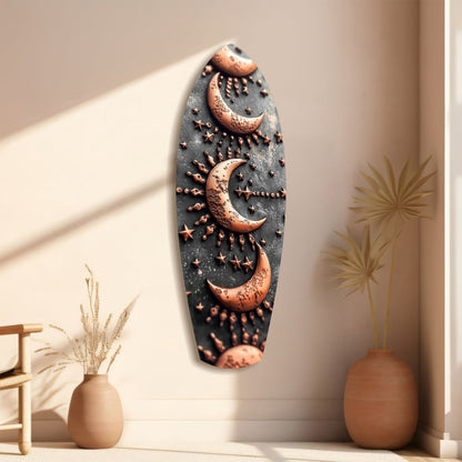 Black glass wall art with copper moons and stars hanging in beige interior with decorative vases and dried plants.
