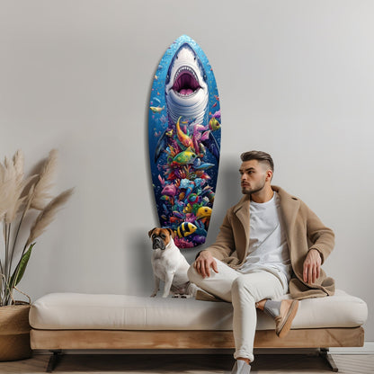 Man and dog sitting on beige sofa beneath oval glass wall art featuring white shark with open mouth above colorful coral reef and tropical fish.