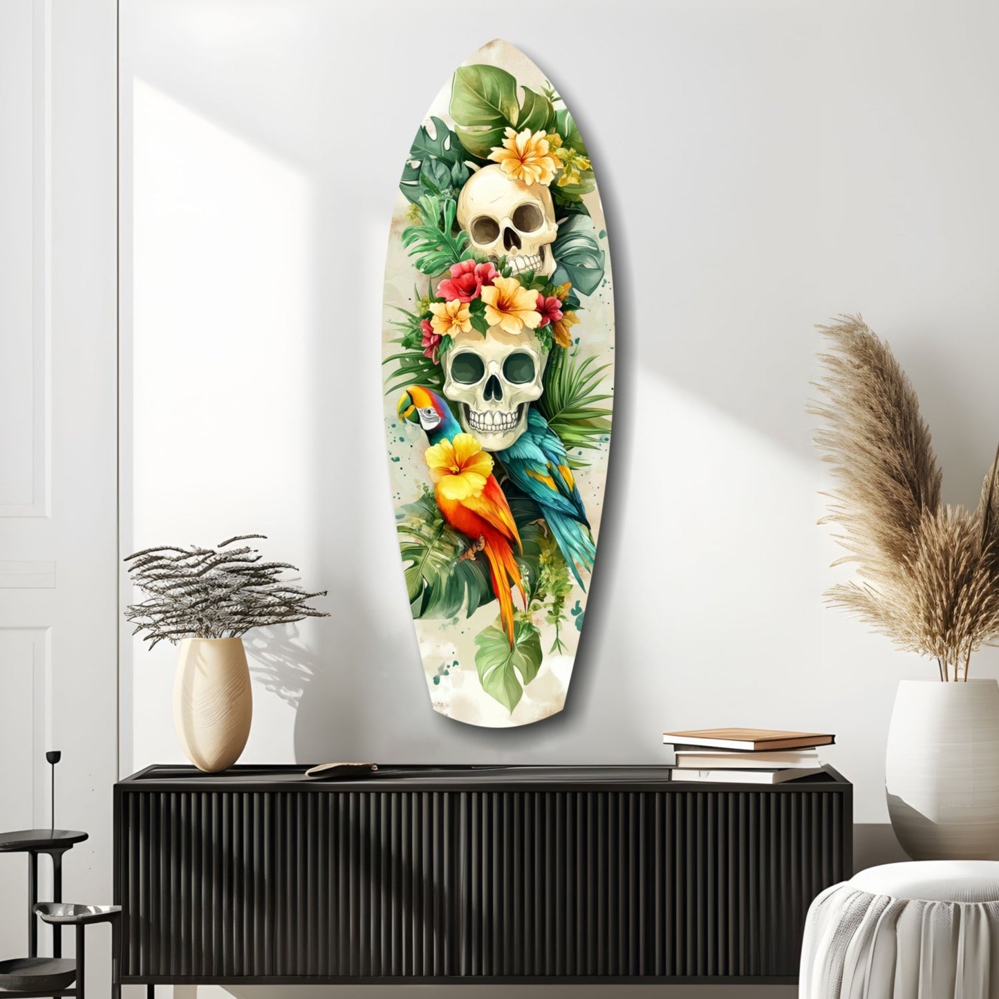 Oval glass wall art featuring two stacked skulls surrounded by tropical flowers, green foliage, and colorful parrots on cream background, displayed above black cabinet.