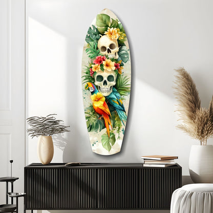 Oval glass wall art featuring two stacked skulls surrounded by tropical flowers, green foliage, and colorful parrots on cream background, displayed above black cabinet.