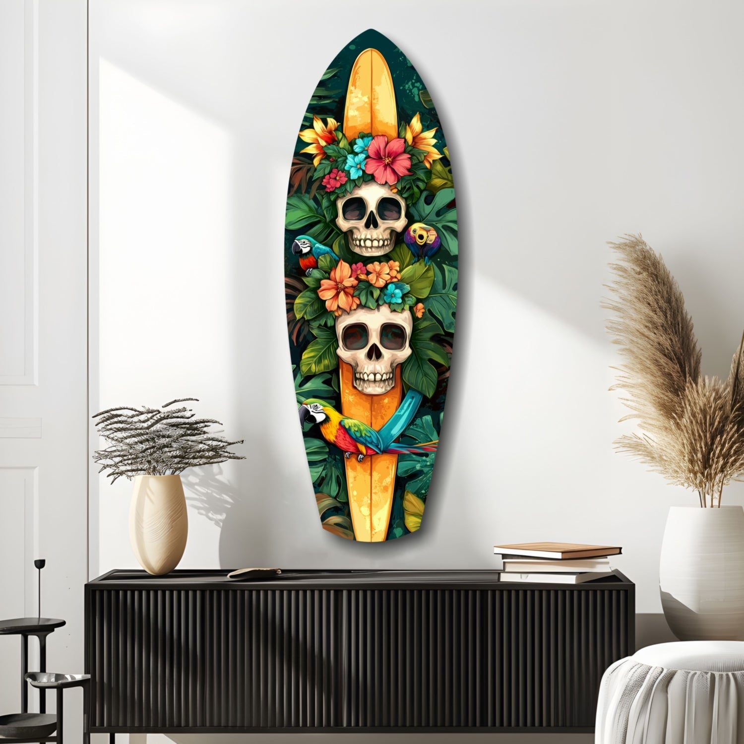 Surfboard-shaped glass wall art featuring two skulls adorned with colorful tropical flowers, parrots, and foliage on dark background, displayed above black cabinet in modern room setting.