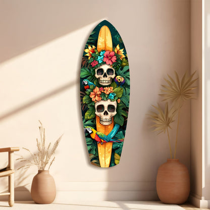 Surfboard-shaped glass wall art featuring two skulls adorned with colorful flowers and parrots, displayed on a beige wall beside ceramic vases.
