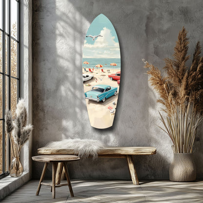 Surfboard-shaped glass wall art depicting retro beach scene with vintage blue car, umbrellas, and seagull, displayed in coastal interior setting.