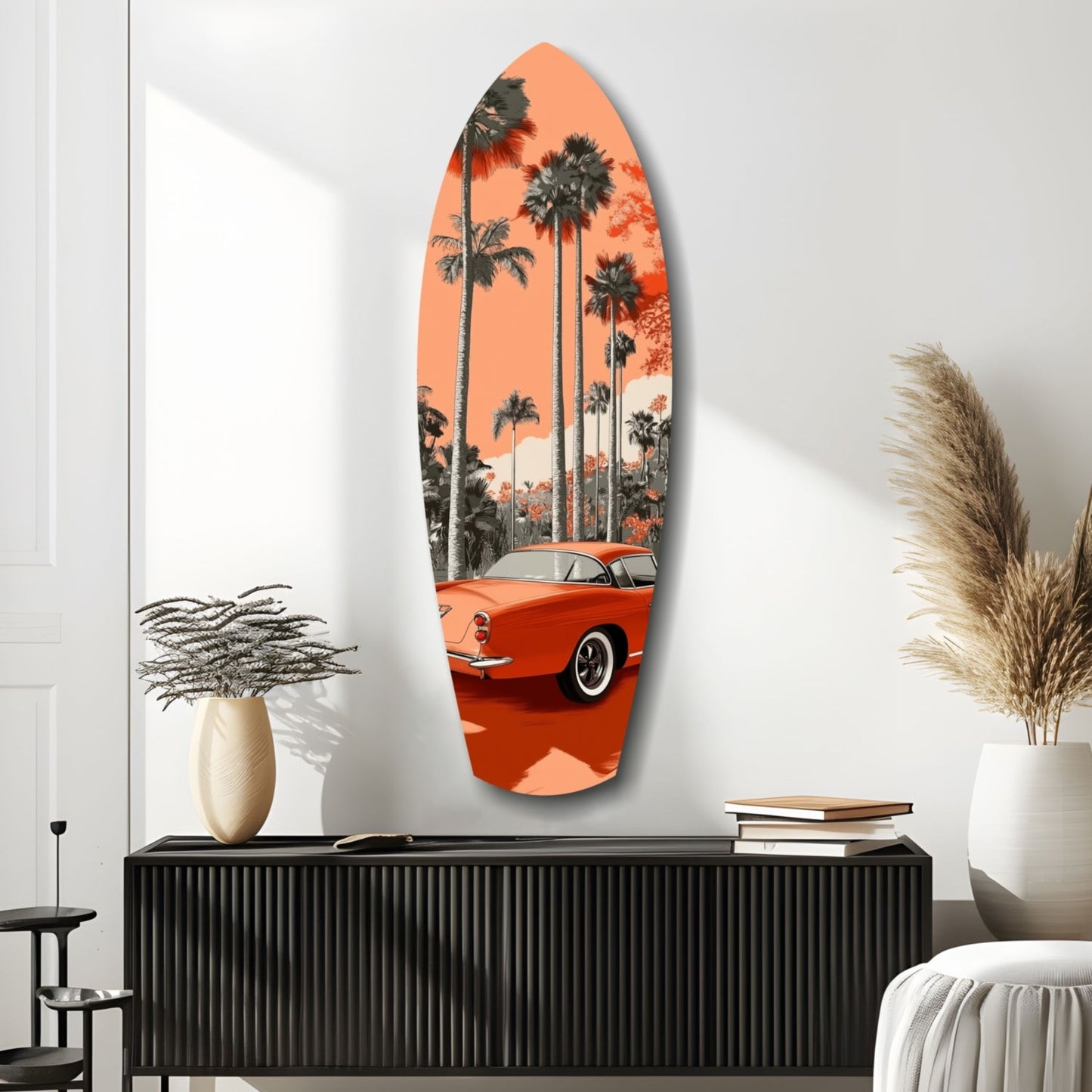 Orange surfboard-shaped glass wall art featuring a vintage red car and palm trees against a coral sunset, displayed above a black console table.