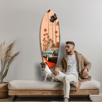 Man in beige cardigan seated on white bench beside surfboard-shaped glass wall art depicting vintage car and palm trees.