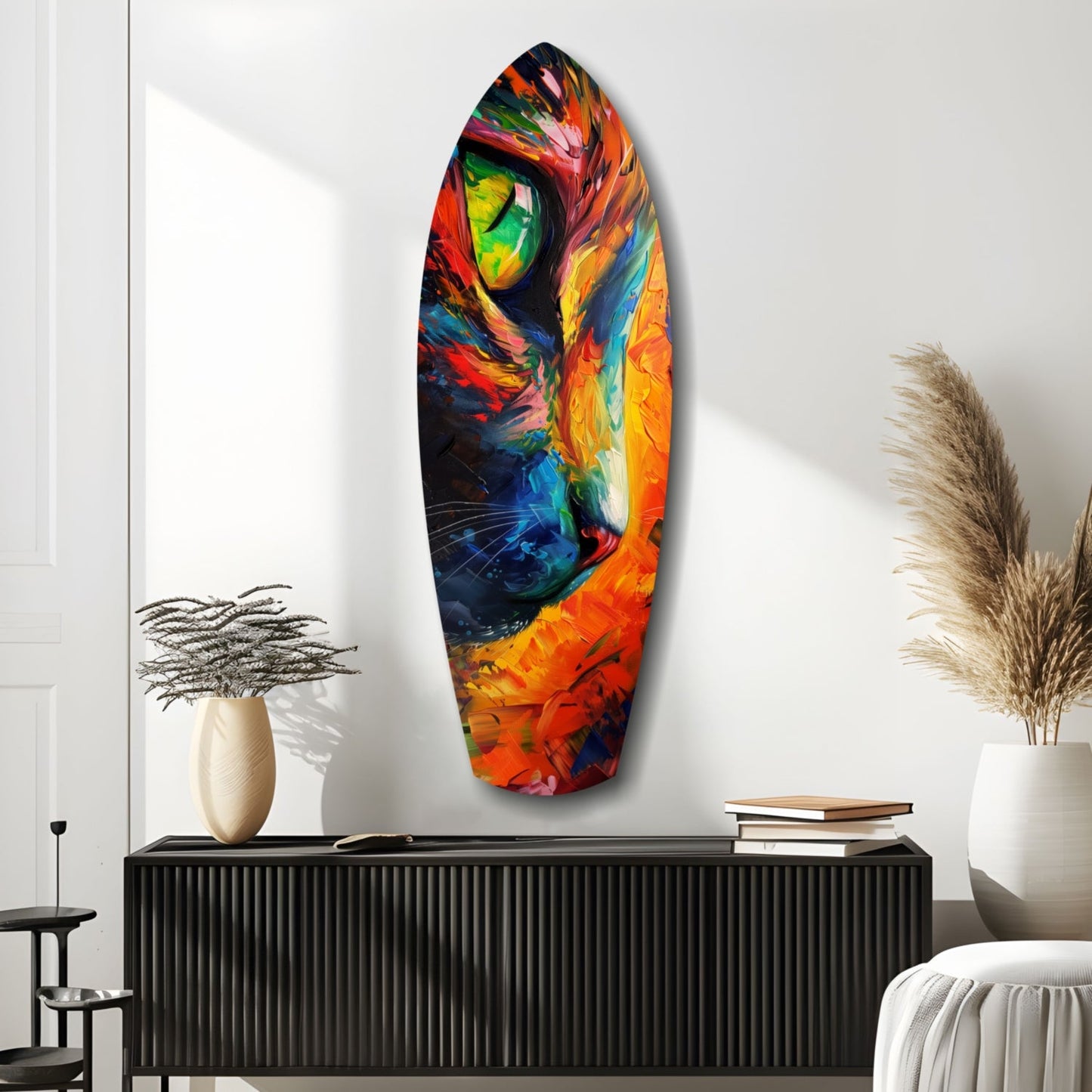 Colorful glass cat wall art hung above a black cabinet in a minimalist room with decorative vases and books.