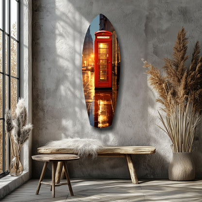 Oval glass wall art depicting illuminated red British telephone booth displayed above wooden bench in minimalist room with dried pampas grass.