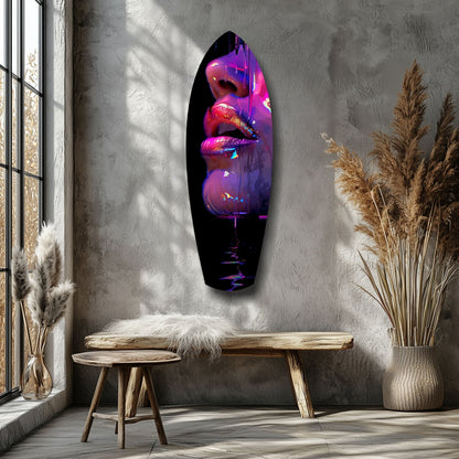 Neon pink and purple illuminated glass lips art displayed on grey wall above wooden bench in minimalist room.