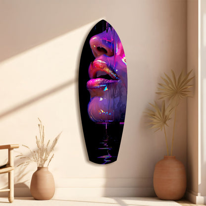 Neon pink and purple lips glass wall art hanging vertically on beige wall beside ceramic vases and dried grasses.