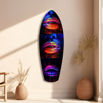Oval black glass wall art displaying three neon-glowing lips in red, pink, and purple, mounted vertically between ceramic vases with dried flowers.